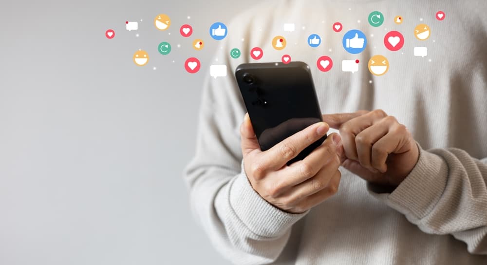 An adult man holding a smartphone, browsing a social media network application.