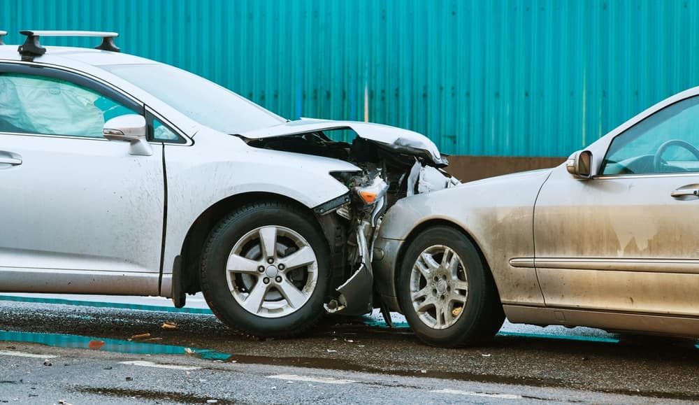 A car collision accident on the street, with two cars involved in a front-end crash.