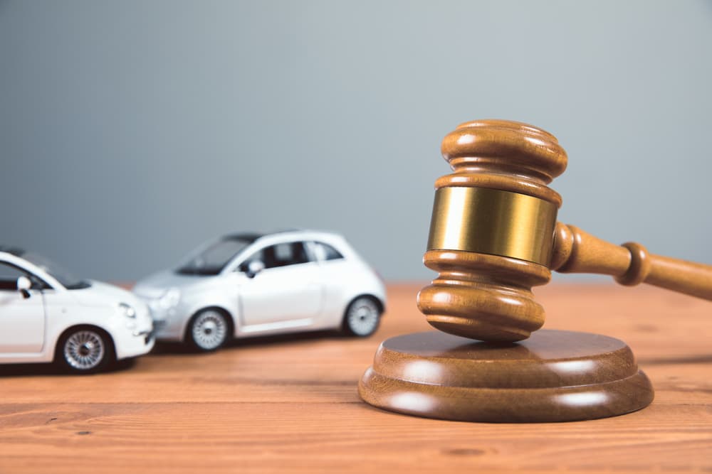 A court gavel rests on a table surrounded by toy cars, symbolizing a car accident case or legal proceedings.