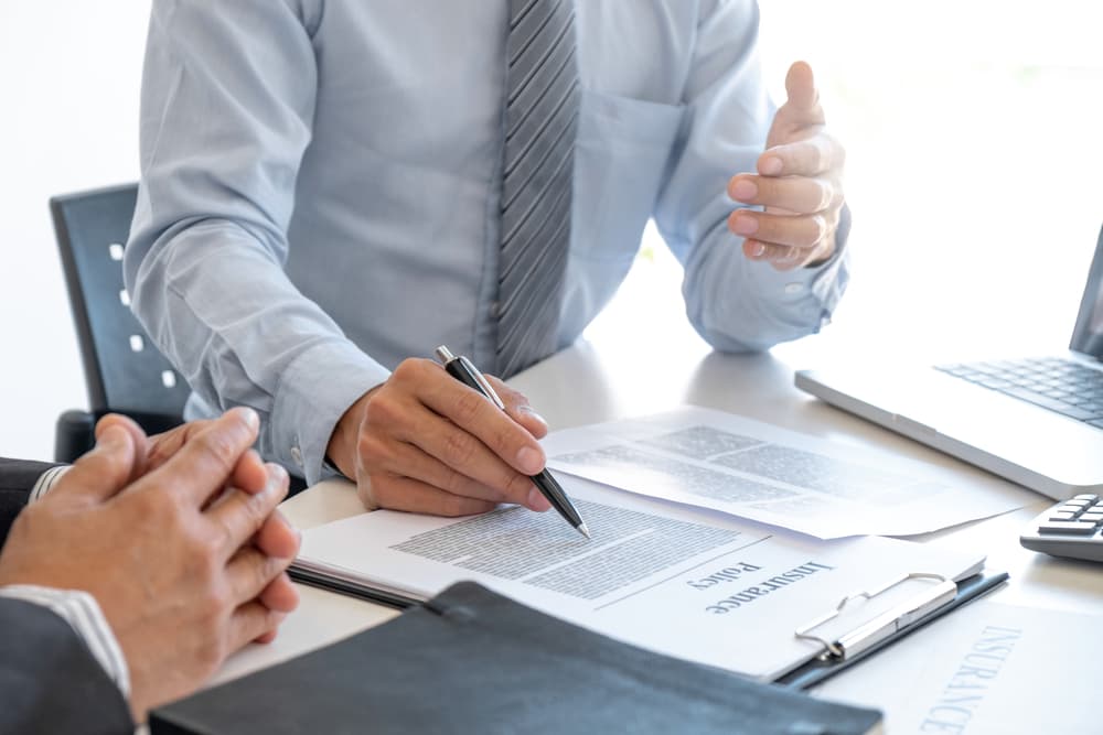 An insurance agent reviewing and explaining an insurance policy to a customer, highlighting key terms and coverage details in a professional office setting.