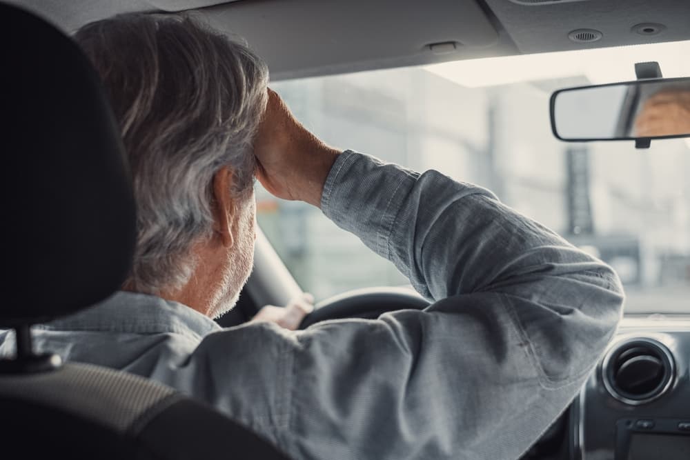 Stressed old person feeling headache in car, stop the car, keeping hand to head and feeling anxiety.
