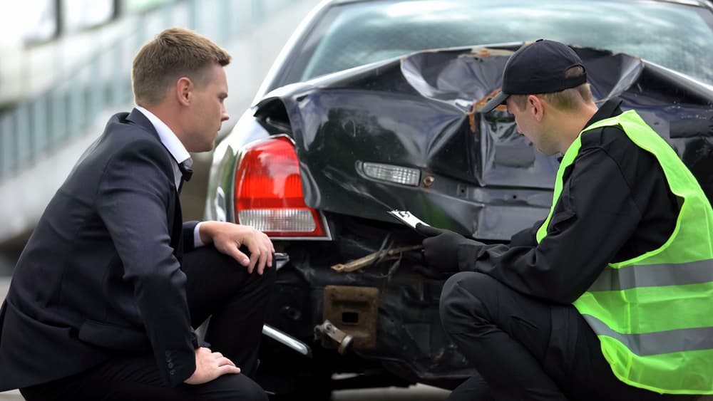 A police inspector filling out a car accident report, analyzing damage, with a stressed driver nearby.