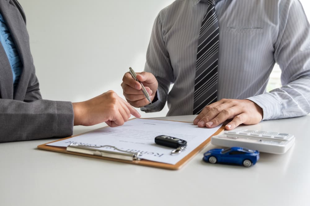 The car dealership offers guidance on insurance details and rental information, finalizing the process by handing over the keys after the rental contract is signed.