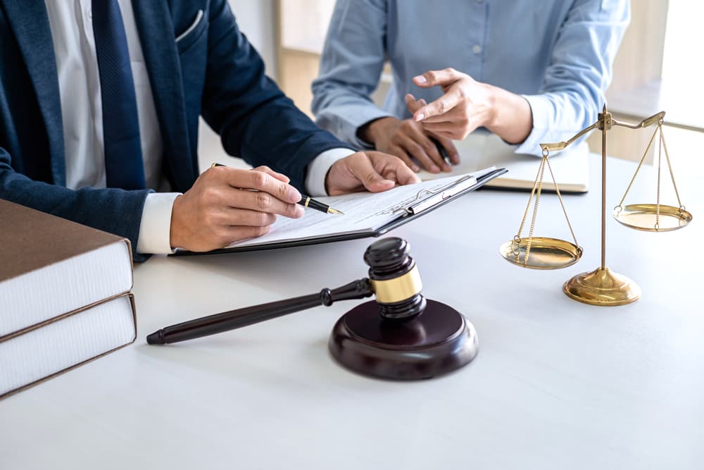 A female and male lawyer or judge consulting and holding a team meeting with a client at a law firm office, representing law and legal services.