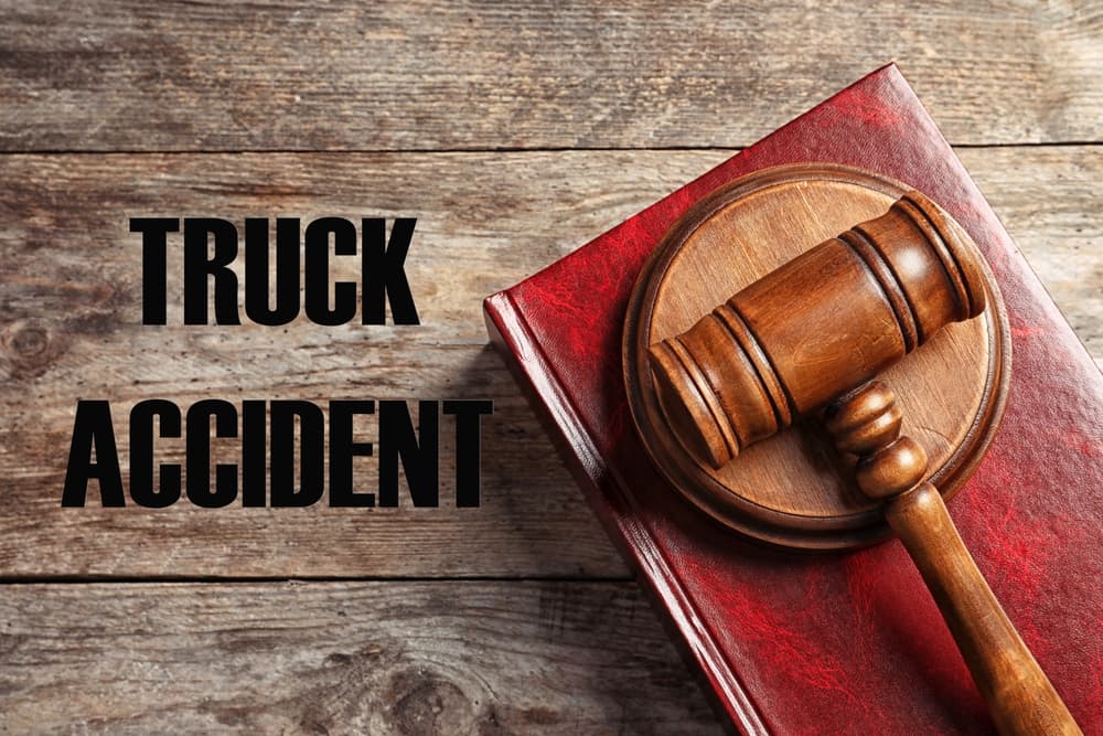Truck accident law concept with a judge's gavel and legal book placed on a wooden table, viewed from the top.