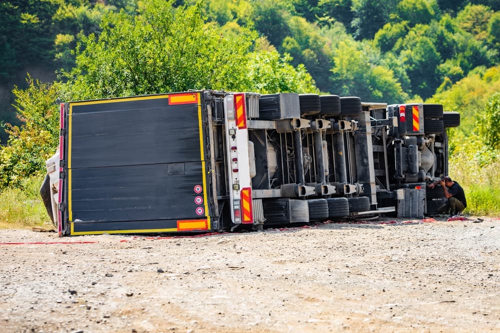 Overturned large cargo truck on the road after a daytime traffic accident.