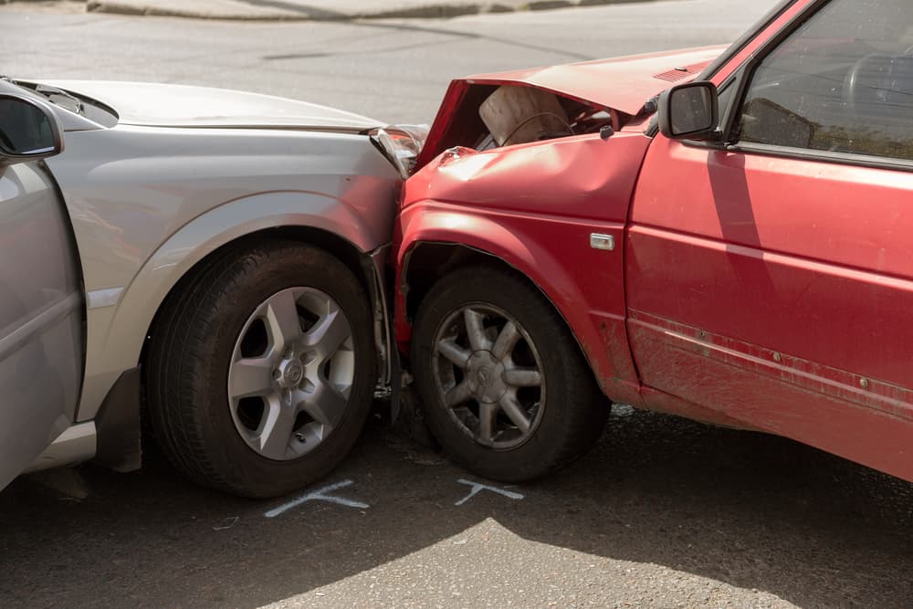 Damaged cars after a head-on collision on a city street in Athens, GA, illustrating a car crash caused by driving rule violations and an insured event.
