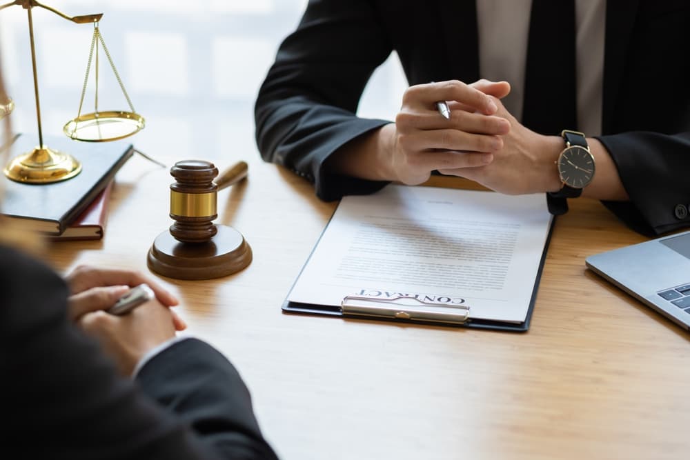 A lawyer explaining a legal contract to a client and guiding them to sign it.