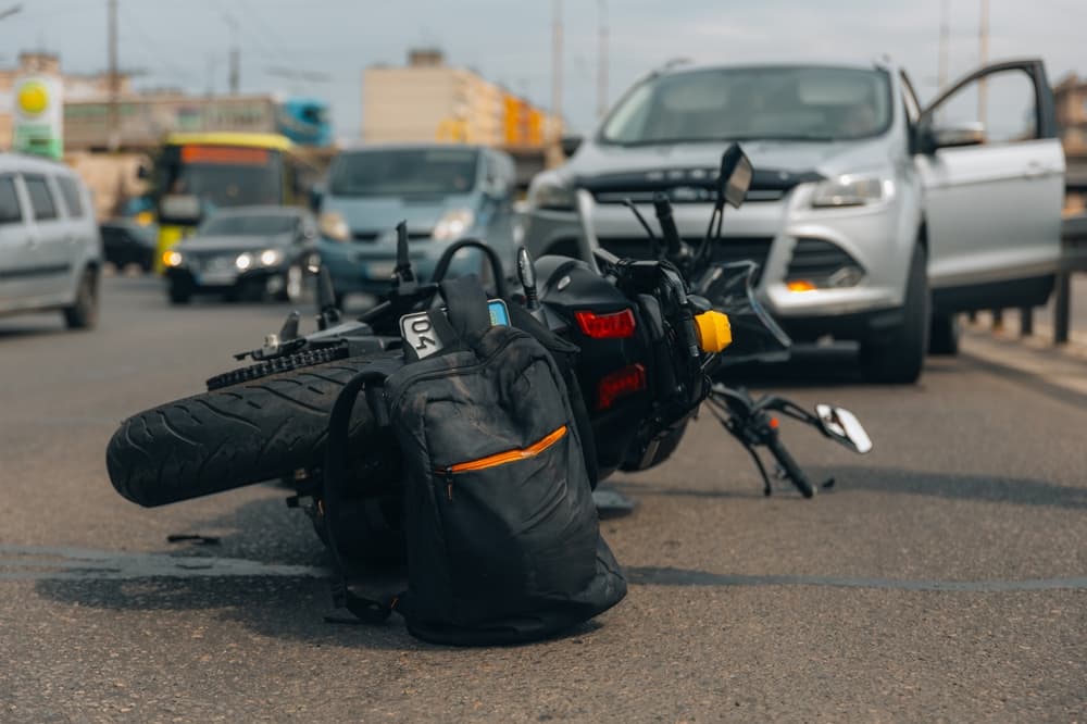 A motorcycle lies on the sidewalk after a serious accident, possibly due to loss of control or a collision with another vehicle.