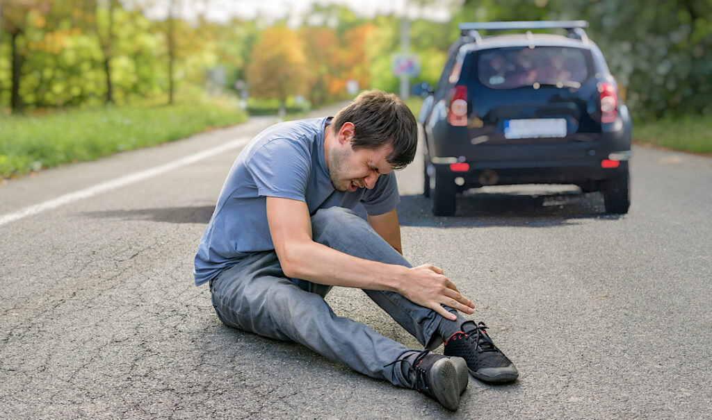 Hit and run concept. Injured man on road behind car in Athens, GA.